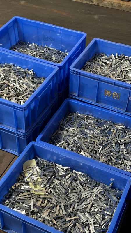 Die-cast zinc alloy window handle raw castings stored in blue industrial crates for bulk assembly