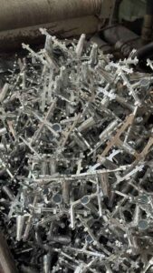 Unfinished zinc alloy window handle bases piled for deburring and surface treatment.